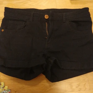 Svarta shorts från H&M - Snygga svarta shorts från H&M med klassisk design. De har en dragkedja och knapp framtill samt fickor både fram och bak. Perfekta för en avslappnad stil.