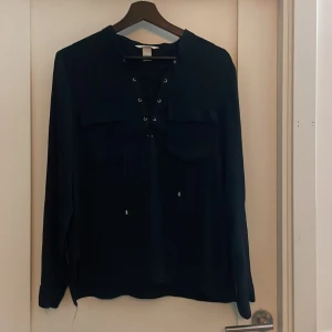 Fin mörkblå blus ifrån H&M - Superfin mörkblå blus ifrån H&M med tvp fickor och knytning där fram. Materialet är runt och jätteskönt och blusen sitter fint på. Använt ett fåtal gånger bara!