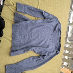 Blå stickad tröja - Säljer en stilren blå stickad tröja med v-ringning. Tröjan har långa ärmar och ribbade muddar vid ärmslut och nederkant. Perfekt för kyligare dagar.🌸💕🌸💕