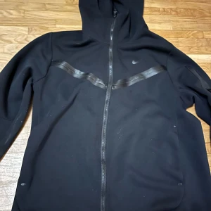 Svart hoodie från Nike - Använd nike tech Hoodie den ser ändå bra ut med bra quality. Inga fläckar ser inte helt ny ut men it jätte använt heller. Ser lite smutsig ut på bilden men i verkligheten kommer den se bra ut. Pris kan sänkas och diskuteras.