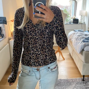 Leopardmönstrad långärmad topp från XOXO - Säljer en snygg leopardmönstrad topp från XOXO. Den har långa ärmar och en tight passform, perfekt för att ge en trendig look. Toppen är gjord i ett mjukt och stretchigt material som sitter bekvämt. Perfekt för dig som vill sticka ut med ett djärvt mönster! 🐆