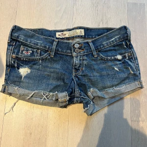 Blå jeansshorts från Hollister - Snygga blå jeansshorts från Hollister med slitna detaljer och upprullade kanter. Midja: 38. Inga bilder på 
