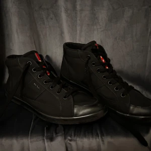 Prada skor - Snygga svarta skor från Prada med klassisk design och snörning. Skorna har en diskret logotyp på sidan och en röd detalj. Det finns inga stora defekter på skorna men man ser ju på sula att skorna har varit använda. Hör av er gärna om ni har frågor. 