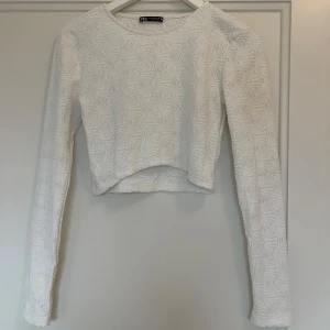 Vit topp från Zara - Vit topp från Zara med ett texturerat mönster. Den är använd endast 2-3ggr. Tyget är stretchigt. Den är i storlek M men passar S också!