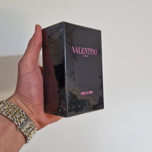 Valentino Uomo Born in Roma 100ml  - Säljer en lyxig parfym från Valentino, Uomo Born in Roma. Flaskan innehåller 100 ml och kommer i en elegant svart förpackning med rosa text. Perfekt för den som vill ha en sofistikerad och modern doft.