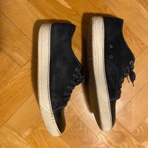 sneakers från Lanvin - Snygga sneakers från Lanvin i mocka med vita sulor. Skorna har snörning och en stilren design. Perfekta för en avslappnad men stilfull look.