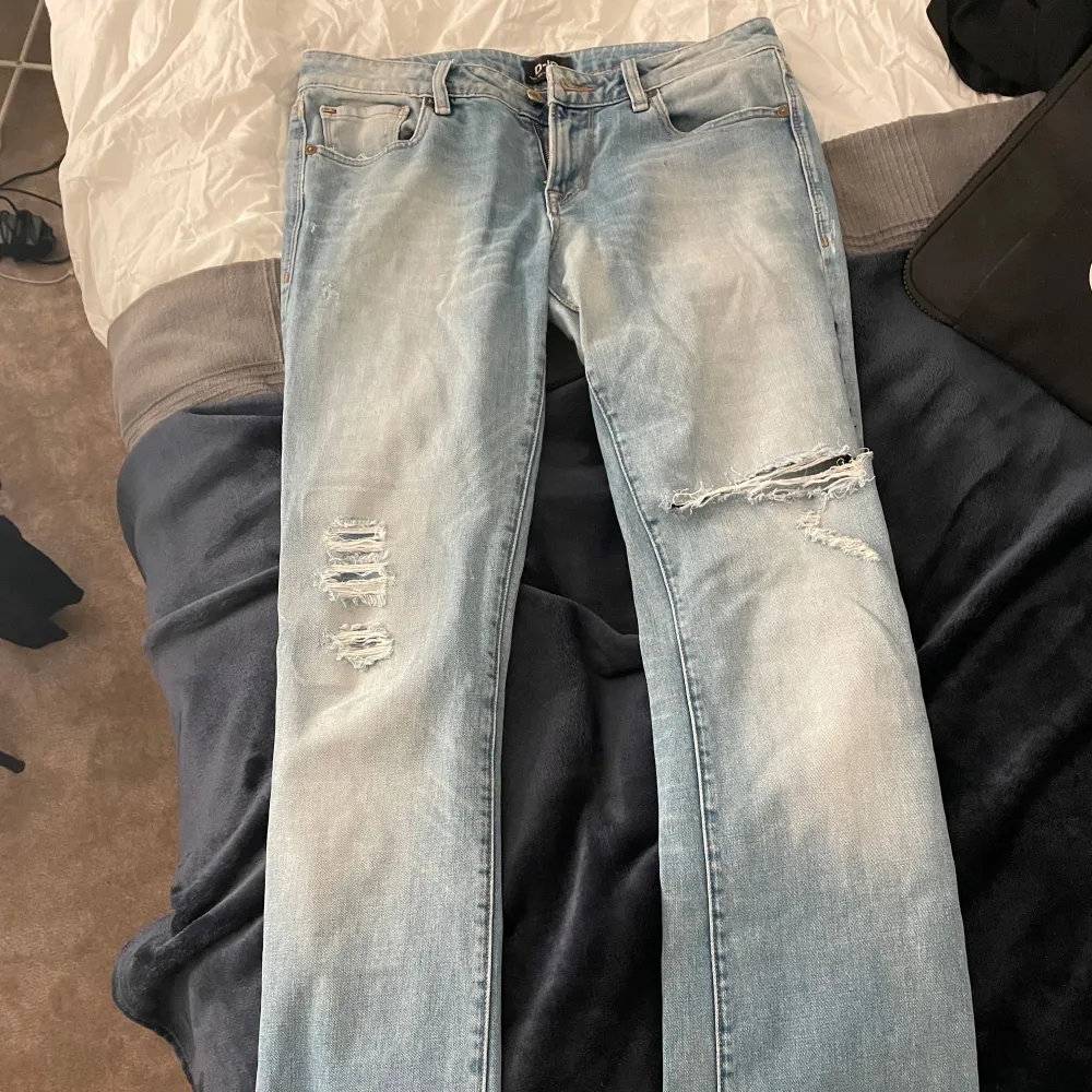 Snygga lågmidjade bootcut jeans med slitningar på låren. Storlek 27 men skulle säga att de lutar åt 28! Har ett litet större hål vid knät än på första bilderna😊Har även lagat jeansen pågrund av att de gått sönder(se bild 4 & 5) Men det är inget som syns på utsidan🥰 . Farkut & Housut.