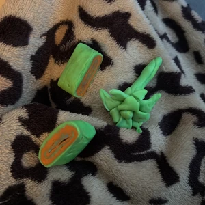 Handgjorda gröna och orangea lerskulpturer - Unika handgjorda lerskulpturer i grönt och orange. Skulpturerna består av två delar, en rullad form och en abstrakt form. Perfekt för dekoration eller som en kreativ present.