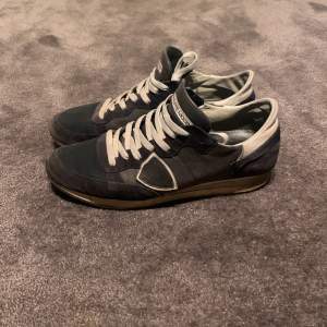Snygga mörkblå sneakers från Philippe Model med vita snören och detaljer. Bra skick 7/10, lite heeldrag men inget som skadar skon. Väldigt sköna. Pris kan diskuteras vid snabb affär!