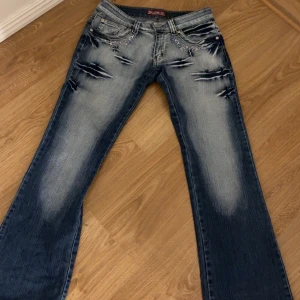 Blå low waist bootcut jeans med broderi - Säljer ett par blå low waist bootcut jeans. De har fina broderier och märken. De har inga hål eller fläckar. De står storlek 36 alltså europeisk så i waist är de 25-26. Passar de med storlek xs/s endast använda 4 gånger 