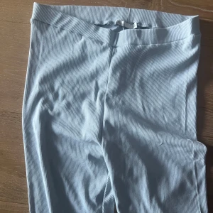 Ljusblå ribbad ziptröja med matchande byxor - Säljer en ljusblå ribbad tröja med dragkedja framtill. Tröjan har lång ärm och är figurnära i modellen. Perfekt att matcha med likadana byxor för en snygg och enkel look.
