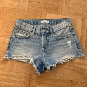 Blå lowwaist jeansshorts från gina  - Säljer ett par ljusblå jeansshorts med fransig kant och slitningar framtill. Klassisk femficksmodell med låg midja och råa benslut. Perfekta för sommaren och enkel att matcha med olika toppar. Älskar dom men har blivit för små!!!! Har säkert bättre bilder men be bara om andra men dom e ju relativt billiga så 💘