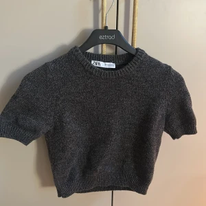 Mörkgrå stickad croppad tröja från Zara - Säljer en mörkgrå stickad croppad tröja från Zara. Den är perfekt för lager på lager outfits!!