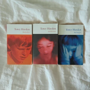 Bokpaket av Torey Hayden: Burpojken, Spökflickan, Rävungen - Tre gripande böcker av Torey Hayden: Burpojken, Spökflickan och Rävungen. Omslagen har porträtt i rött, rosa och blått. Böckerna handlar om barn med svåra livsöden och psykiska utmaningar, skrivna av en erfaren barnpsykolog.