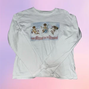 Vit långärmad tröja med änglar - Vit långärmad tröja med tryck av tre änglar och texten 'too blessed to be stressed' i rosa. Tröjan har en avslappnad passform och är gjord i mjukt bomullsmaterial, 100% bomull. Perfekt för en chill och söt look. Tröjan har aldrig blivit använd!