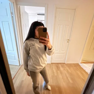 Grå hoodie från Gina Tricot med tryck - Säljer en ljusgrå hoodie från Gina Tricot med texten 'JE M'EN AMOUR' och en stjärna tryckt både fram och bak. Hoodien har långa ärmar, mjukt material och klassisk huva. Perfekt för en avslappnad stil. Kontakta för mer info, pris går att diskutera!