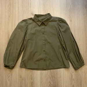 Olivgrön blus - Säljer en olivgrön blus med krage, puffiga långärmar och knappar framtill. Lappen är tyvärr bortklippt men skulle säga att den är typ xxs. Skriv om du har frågor o läs gärna min bio innan du köper🫶🏻💋