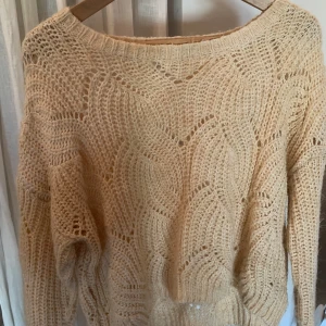 Beige stickad tröja från ONLY - Säljer en beige stickad tröja från ONLY med ett snyggt hålmönster. Tröjan har tre kvarts ärm och rund halsringning, perfekt för lager på lager. Superfin till både jeans och kjol!