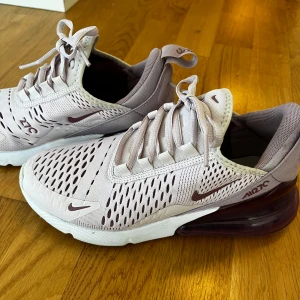 Nike Air Max 270 sneakers i ljuslila och vinröd - Nike Air Max 270 sneakers i ljuslila mesh med vinröda detaljer och stor synlig luftbubbla i hälen. Skorna har snörning och vit sula, samt diskreta Nike-loggor på sidorna och tungan. Perfekta för en sportig och trendig look. Storlek 37,5