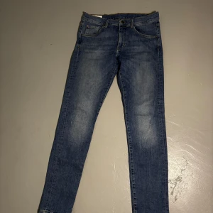 Blå jeansbyxor från J.Lindeberg - Storlek:31/32.                                   Skick:Mycket bra.                            Beskrivning:Säljer ett par klassiska blå jeans från J.Lindeberg med fem fickor och snygga slitningar framtill. Byxorna har normal passform och raka ben, perfekta till vardags. Gula kontrastsömmar och logga på myntfickan.