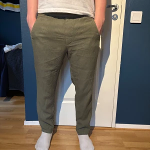 Olivgröna linnebyxor från Zara - Säljer ett par olivgröna linnebyxor från Zara i storlek L. Byxorna har normal passform, resår i midjan och raka ben. Perfekta för varmare dagar och ger en avslappnad men stilren look.