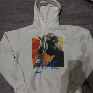 2pac hoddie - Säljer en vit hoddie med stort tryck av 2pac, köpt för 900kr och har andvönds runt 3 gånger. Så i väldigt bra tryck.
