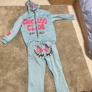 Ljusblå mjukisbyxor med monstertryck - Ljusblå mjukisbyxor med stort monsteransikte i svart, vitt och rosa framtill. Byxorna har resår i midjan och är i en avslappnad passform. Perfekta för en cool och lekfull stil.