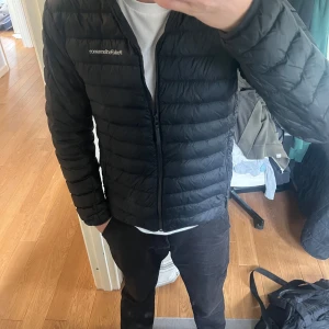 Svart dunjacka från Peak Performance - Säljer en svart dunjacka från Peak Performance med huva och dragkedja. Jackan är quiltad och har en stilren design med logga på bröstet. Perfekt för nu när de blir lite varmare och enkel att matcha med olika outfits. Använd fåtal gånger och inga defekter! Hör gärna av er om ni har några frågor!🙌🙌