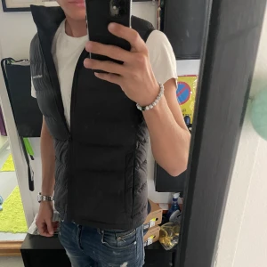 Svart dunväst från Peak Performance - Snygg svart dunväst från Peak Performance med dragkedja framtill. Perfekt för lager-på-lager under kyliga dagar. Diskret logga på bröstet ger en stilren look. Nypris 2,500kr säljs nu för 800kr, skriv för mer bilder och funderingar. Passar även för damer🤩🤩🤩