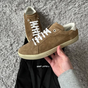 Saint Laurent SL/06 - Ett par sköna och eftertraktade Saint Laurent sneakers! | De är i mycket fint skick har små tecken på användning som syns på bild men de är knappat märkbara! Färgen är lite ljusare än vad som syns på bild! | Dustbag tillkommer! | Storlek 41,5. | Ställ gärna frågor innan du köper!