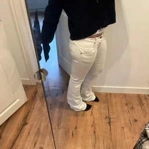Vita Lågmidjade bootcut jeansbyxor - Midjemått:40cm passar nån som e 1,60 Säljer ett par vita bootcut jeansbyxor med klassisk femficksdesign och bälteshällor.  Perfekta för en fräsch och stilren look.