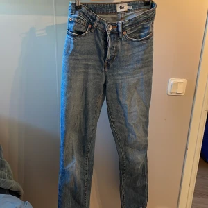 Blå jeansbyxor från 157 - Klassiska blå jeansbyxor från 157 med normal passform och raka ben. Byxorna har knappar i gylfen, fem fickor och orangea sömmar. Har ett hål mellan benen som man enkelt kan laga. Perfekta för en avslappnad stil och passar till det mesta.