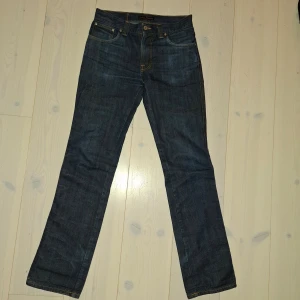 Nudie Jeans Slim Jim W30 L34 - Mörkblå jeans från svenska Nudie. Byxorna har passform Slim Jim och tvätt Dry Broken Twill. W30 L34 och sitter bra på mig som är 190cm lång. Säljer då de nu är lite för slim fit för min smak. Bara att skriva vid minsta fråga!