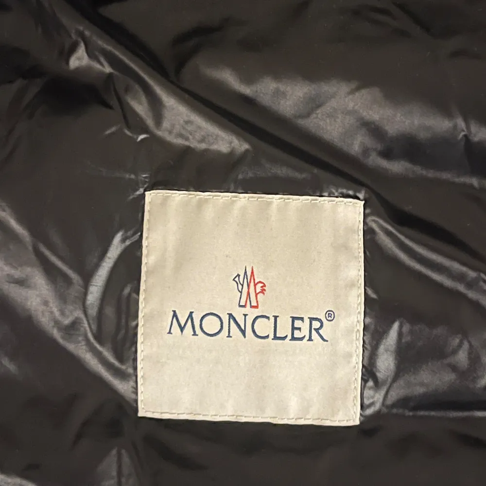 Snygg svart dunväst från Moncler med dragkedja och logotyp på bröstet. Perfekt för kyliga dagar. Takit.