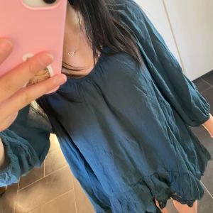 Blå blus från KappAhl 💕 - Säljer en luftig blå/turkos blus/klänninh från KappAhl med volangdetaljer vid nederkanten. Blusen/klänningen har trekvartsärmar och en rundad halslinje. Perfekt för en avslappnad stil. Den hade en berlock som jag tog av men jag kan sätta på den igen ifall det önskas. Pris kan diskuteras 💕