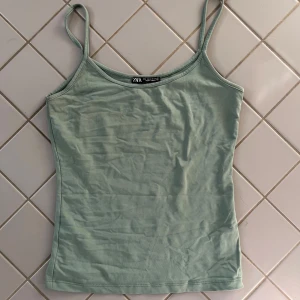 Grön linnetopp från Zara - Säljer en stilren grön linnetopp från Zara. Toppen har smala axelband och en enkel design som passar perfekt till sommaren. Materialet är mjukt och bekvämt. Den är använd endast ett fåtal gånger och i mycket bra skick, kom gärna privat för frågor eller fler bilder ☺️