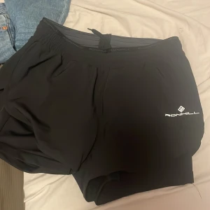Svarta träningsshorts från Ronhill mm - Säljer ett par svarta träningsshorts från Ronhill. De är perfekta för löpning eller gymmet och har en bekväm passform med elastisk midja. Shortsen är tillverkade i ett lätt och andningsbart material. Finns också vanliga kläder som jeans mm