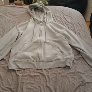 Grå hoodie från H&M Divided - Säljer en grå hoodie från H&M Divided. Den har en dragkedja framtill och en klassisk huva. Perfekt för en avslappnad stil. Hör av dig vid intresse!