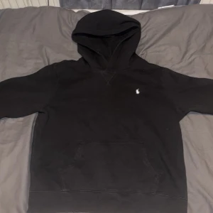 Svart hoodie från Ralph Lauren S - Säljer en klassisk svart hoodie från Ralph Lauren med den ikoniska broderade loggan på bröstet. Hoodien har en rymlig ficka framtill och en bekväm huva. Perfekt för en stilren och avslappnad look. Priser är ej hugget i sten. Var inte rädda för frågor. Först till kvarn