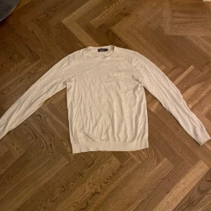 Beige tröja från Dressmann - Säljer en stilren beige tröja från dressmann. Tröjan har en klassisk design med rund hals och långa ärmar. Perfekt för en avslappnad men ändå snygg look. Passar bra till både jeans och chinos.