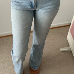 Ljusblå straight jeans från Gina Tricot - Säljer ett par ljusblå jeans från Gina Tricot med klassisk femficksmodell och raka ben. Jeansen har normalhög midja och är tillverkade i bomull med en snygg tvättad look. Perfekta för en chill och stilren vibe.