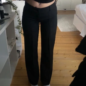 Svarta kostymbyxor med raka ben - Säljer ett par svarta kostymbyxor från madlady i storlek 34/reg låg midja och raka ben. Byxorna har pressveck framtill och en klassisk, stilren look som passar till många olika outfits. Materialet känns mjukt och följsamt, perfekt för dig som gillar en clean och enkel stil. ‼️Det ända som är defekt på dom är att sömmen längst ner på benet är uppsprätt på bägge benen, den ända som hänt är att dom så är längre i benen än vanlig reg längd. 