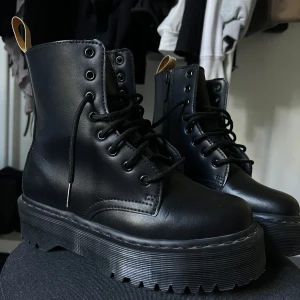 Svarta boots med platåsula och snörning - Tuffa svarta boots i skinnimitation med grov platåsula och snörning framtill. Dragkedja på sidan för enkel påtagning och rund tå. Perfekta för dig som vill ha en edgy look och extra höjd. Snygga detaljer med svarta sömmar och robust yttersula.