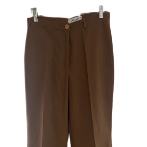 Bruna vida kostymbyxor - Stilrena bruna kostymbyxor från Moditti med vida ben och klassisk passform. Fint skick och bekväma att bära. Använda max en gång. Säljes pga garderobsrensning. Snabb leverans!📦 