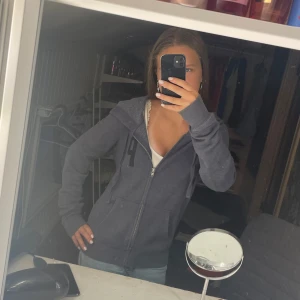 Mörkgrå hoodie från PINK med dragkedja - Mörkgrå hoodie från PINK med dragkedja framtill, huva och fickor. Stor svart bokstav 'P' på bröstet och texten 'LOVE PINK' i svart på ryggen. Perfekt för chill dagar. Mjuk bomullsblandning och långärmad modell.