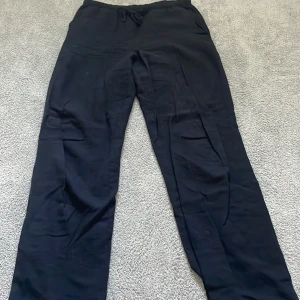 Svarta linne  byxor från Gina Tricot - Svarta linne byxor från Gina Tricot med rak passform och resår i midjan samt snörning. Tillverkade i ett mjukt och lätt material som känns skönt mot huden. Perfekta för en chill och avslappnad stil.