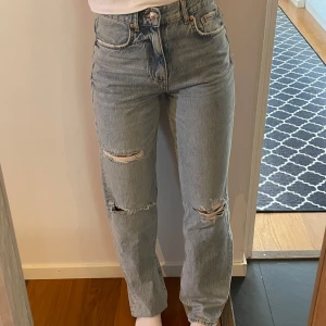 Raka ljusblå jeans med slitningar Ginatricot - Raka ljusblå jeans från Perfect Jeans Ginatricot, med hög midja och raka ben. Jeansen har slitningar på båda benen och klassisk femficksdesign. Storlek 34