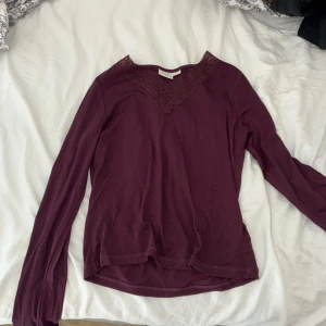 Vinröd långärmad topp med spets Gina Tricot - Supersnygg vinröd långärmad topp från Gina Tricot med v-ringning och spetsdetalj vid halsen. 