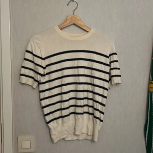 Randig kortärmad tröja från Zara - Vit och marinblå randig tröja från Zara i storlek M. Tröjan har korta ärmar, rund halsringning och bred mudd nedtill. Perfekt för dig som gillar en klassisk men chill stil. Materialet känns mjukt och lätt, troligen bomull eller bomullsblandning.