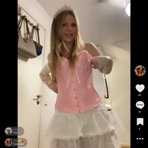 Rosa korsett med rosett och spets - Säljer min Halloween outfit som Törnrosa. Supersöt rosa korsett med glansig yta, spetsdetaljer och en söt rosett framtill. Korsetten har knäppning framtill och fina volangkanter upptill och nedtill. Perfekt för dig som vill sticka ut med en romantisk och feminin look.